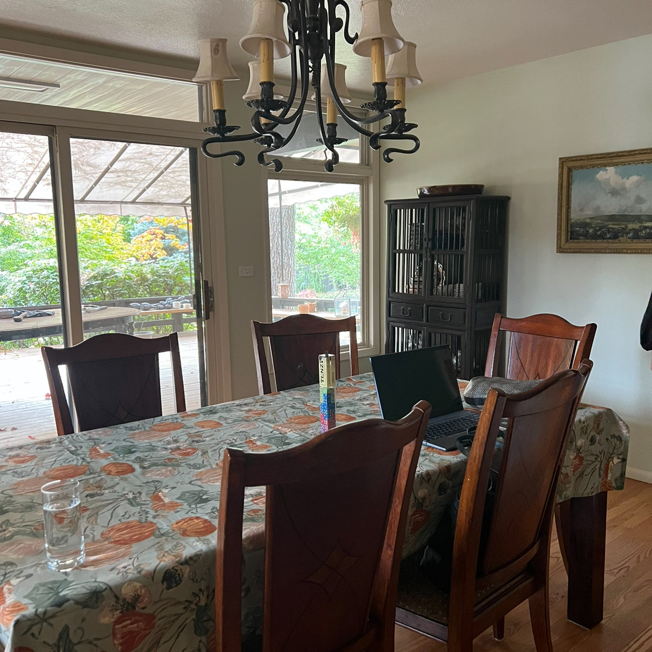 a dining room with dated chandelier and patterned tablecloth before day with a designer