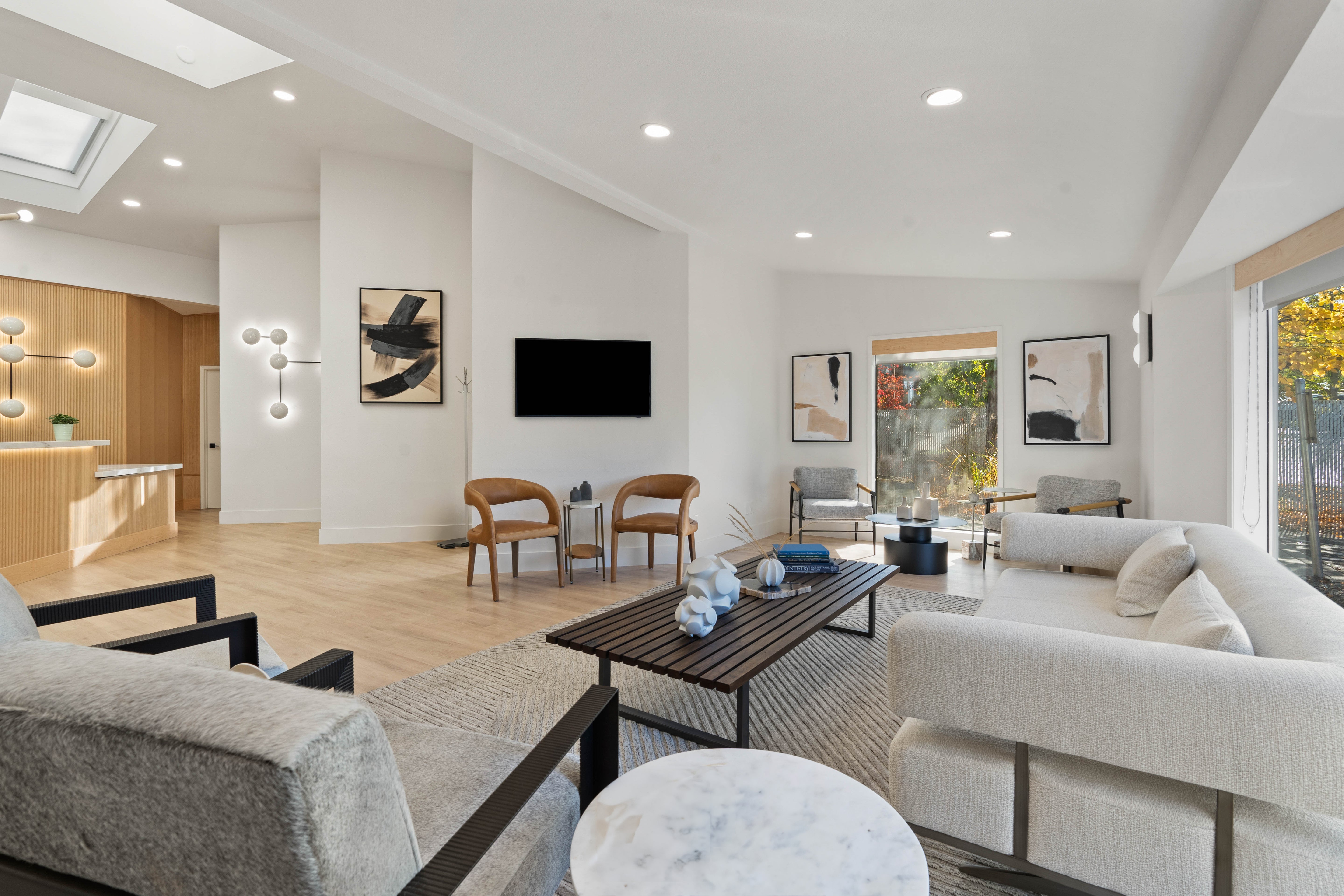 Spacious waiting area with light gray furniture, neutral tones, natural light, and unique decor.