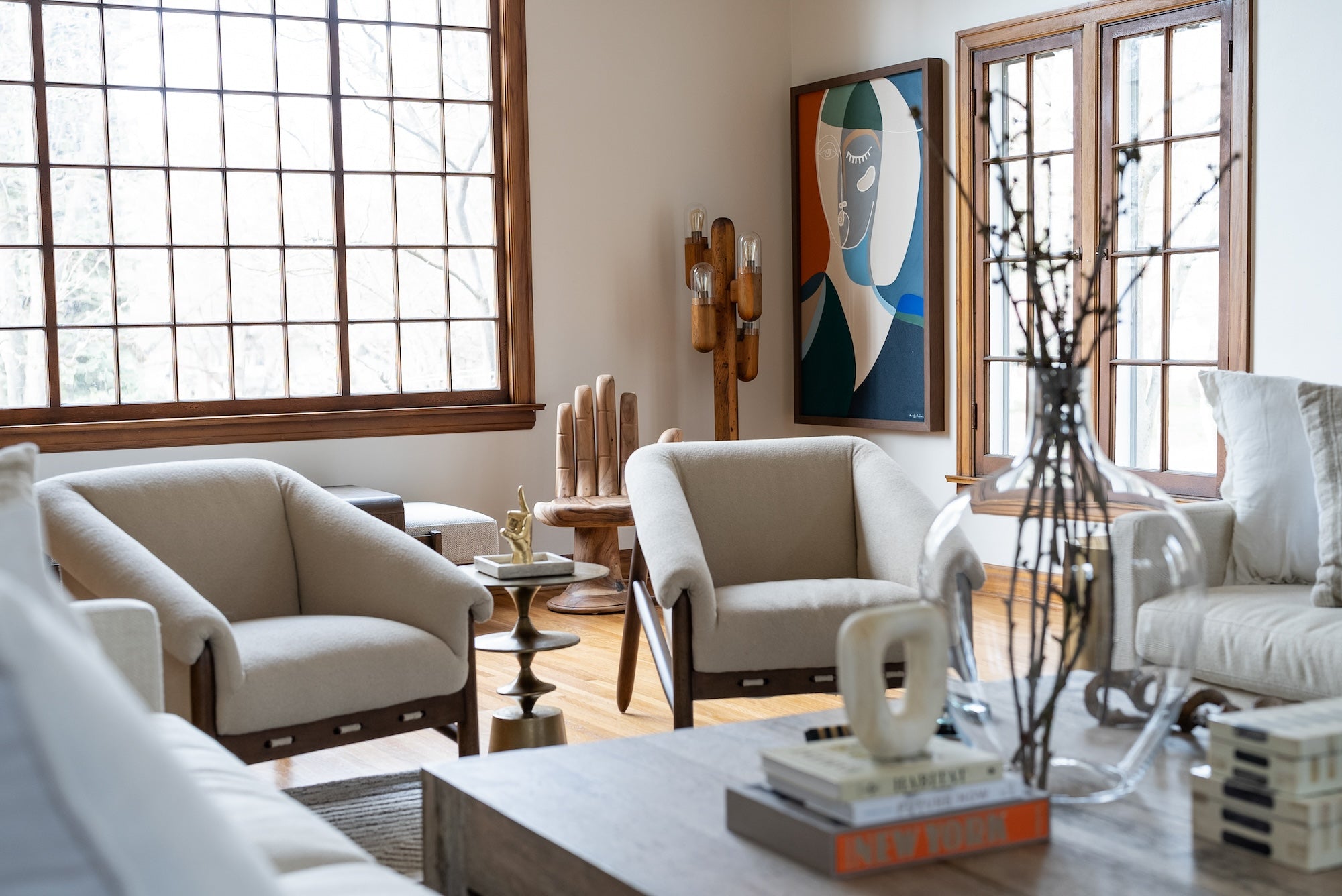 day with a designer living room space with beige chairs, cool table and hand-shaped chair