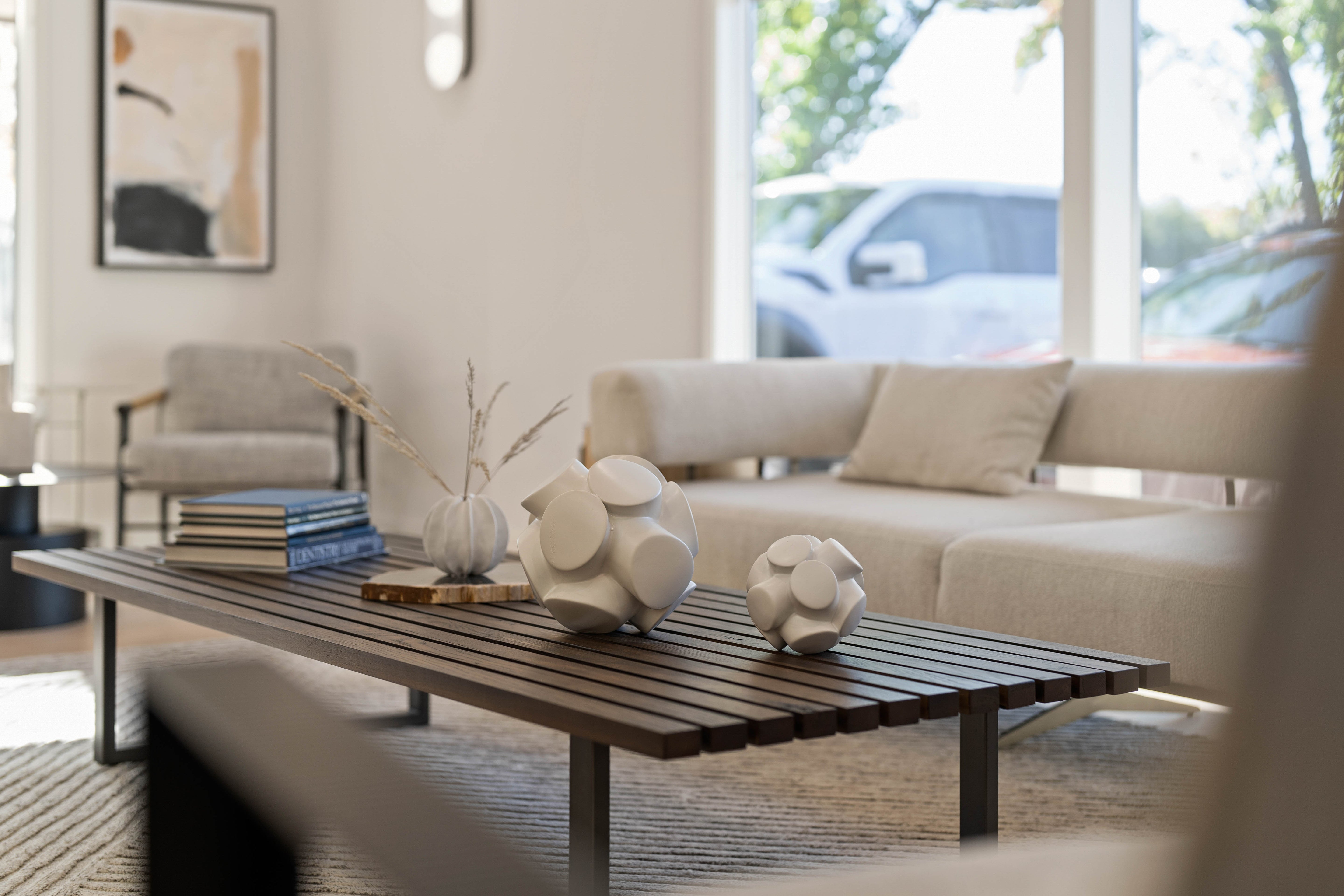 Close up of lobby waiting area, featuring a slatted wood coffee table, abstract ceramic decor, and neutral-toned furniture.