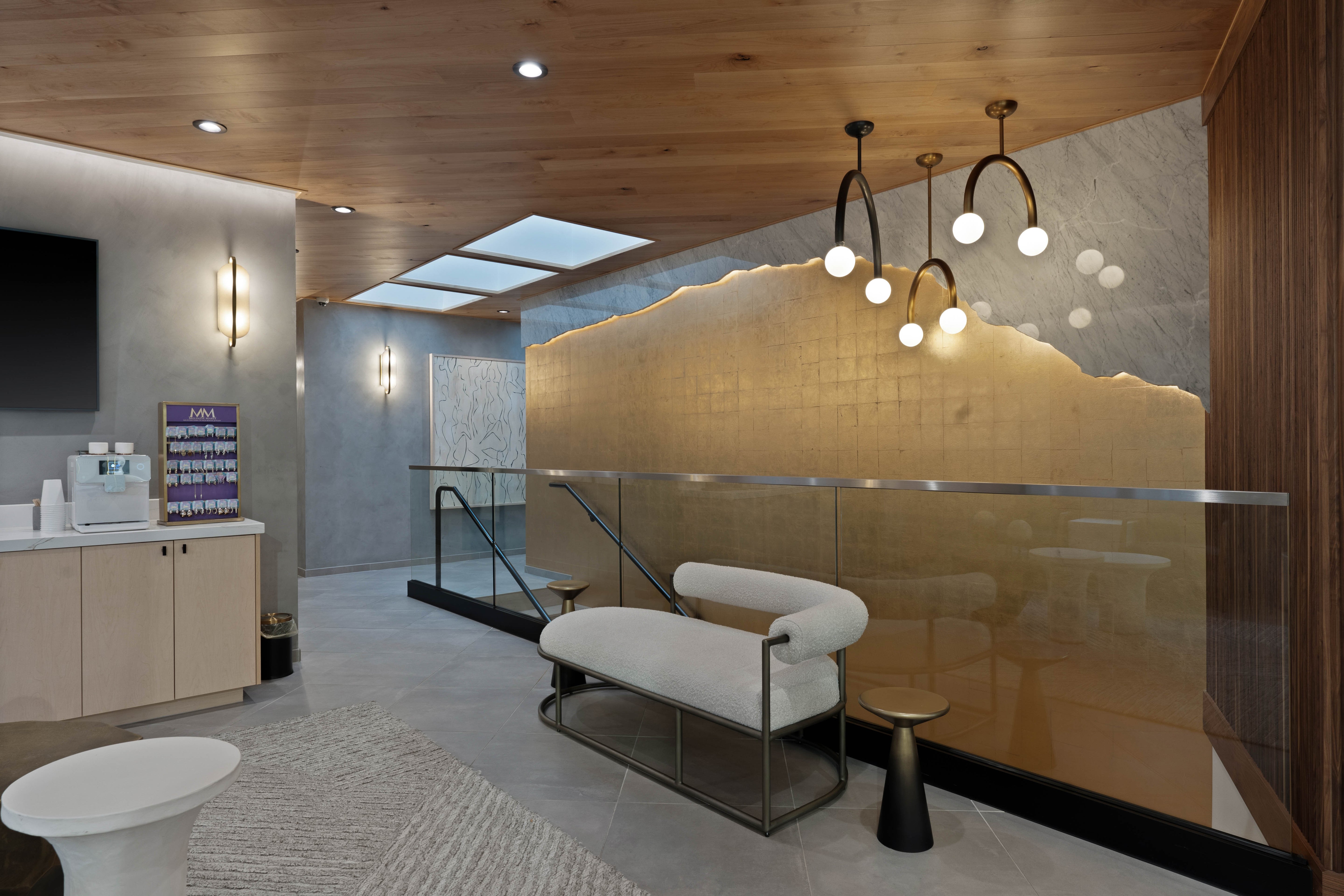 Elegant seating area with a soft white bench, artistic lighting, and a golden accent wall, creating a luxurious and inviting space.